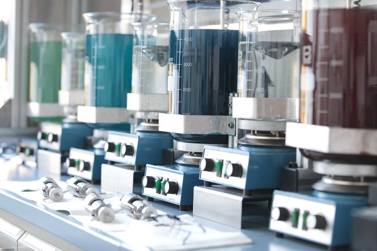 Vrsta laboratorijskih čaš z obarvanimi raztopinami na magnetnih mešalih v proizvodnji Wöhlk